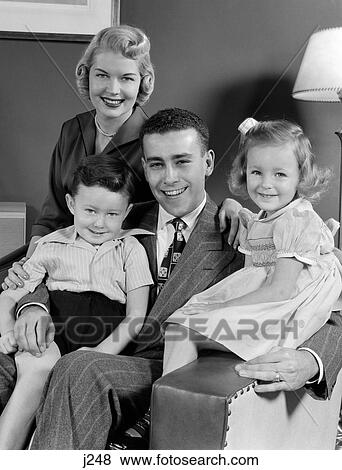 1940S 1950S Family Of Four Portrait Sitting In Living Room Chair Looking At Camera View Large Photo Image Stock Photo - 1940S 1950S Family Of Four Portrait Sitting In Living Room Chair Looking At Camera. Fotosearch