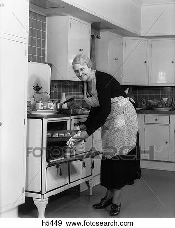 1940S Elderly Woman Taking Pan Of Rolls Out Of Oven Looking At Camera View Large Photo Image Stock Photo - 1940S Elderly Woman Taking Pan Of Rolls Out Of Oven Looking At Camera. Fotosearch