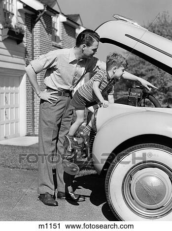 Stock Image - 1940S Father & Son Checking Under Hood Of Car In Driveway. Fotosearch
