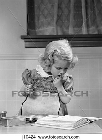 1940S Little Girl Playing In Kitchen Wearing Apron Looking In Cookbook Getting Ready To Bake View Large Photo Image Picture - 1940S Little Girl Playing In Kitchen Wearing Apron Looking In Cookbook Getting Ready To Bake . Fotosearch