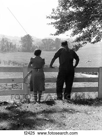 1940S Rear View Of Elderly Farm Couple Standing At Fence Looking Out Onto Pasture View Large Photo Image Stock Photography - 1940S Rear View Of Elderly Farm Couple Standing At Fence Looking Out Onto Pasture. Fotosearch