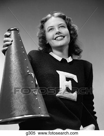 1940S Smiling Girl Wearing A Varsity Sweater With The Letter E On Front Holding A Megaphone With Her Right Hand View Large Photo Image Stock Photography - 1940S Smiling Girl Wearing A Varsity Sweater With The Letter E On Front Holding A Megaphone With Her Right Hand. Fotosearch
