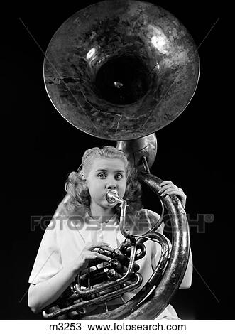 Stock Image - 1940S Teenage Woman Blowing And Playing Tuba Horn Musical Instrument With Eyes Wide Open Looking At Camera. Fotosearch