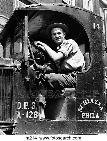 1940S Truck Driver Looking At Camera In Work Shirt & Hat Posed Behind Wheel Of Truck With Open Side No Door View Large Photo Image Picture - 1940S Truck Driver Looking At Camera In Work Shirt & Hat Posed Behind Wheel Of Truck With Open Side No Door. Fotosearch