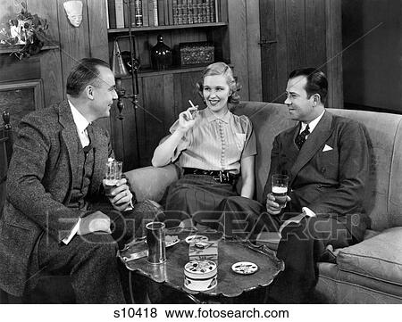 Stock Photo - 1940S Two Men And One Woman Social Group Sitting On Couch Drinking Beer Smoking Cigarettes Talking. Fotosearch