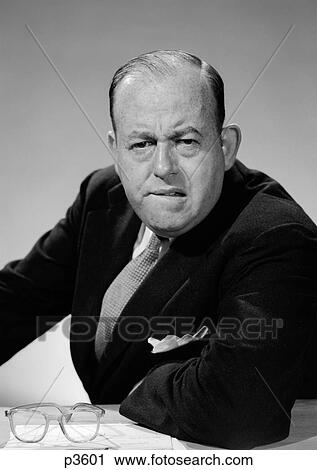 Stock Image - 1950S 1960S Portrait Of Man Businessman Worried Unhappy Frowning Leaning On Desk Looking At Camera. Fotosearch