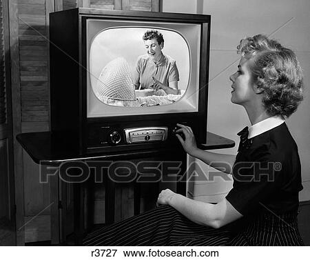 Stock Photo - 1950S Blonde Woman Turning Dial On Tv Set Watching Program About Baby Childcare. Fotosearch