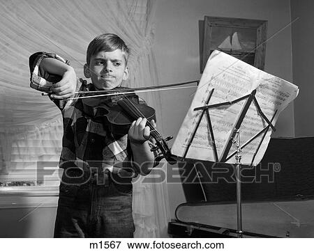 Stock Photo - 1950S Boy In Living Room Practicing Violin With Determined Expression. Fotosearch