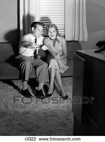 1950S Couple In Darkened Living Room Watching Tv With Husband Pointing At Screen View Large Photo Image Stock Image - 1950S Couple In Darkened Living Room Watching Tv With Husband Pointing At Screen. Fotosearch