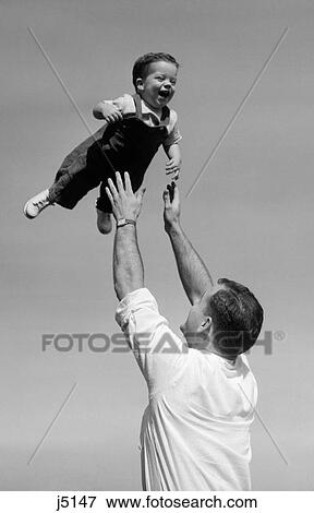Stock Photo - 1950S Father Throwing Baby Son In The Air Outdoor. Fotosearch