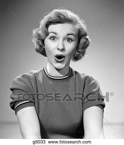 Stock Image - 1950S Head Shot Of Woman Eyes And Mouth Wide Open Surprised Expression Indoor Looking At Camera. Fotosearch