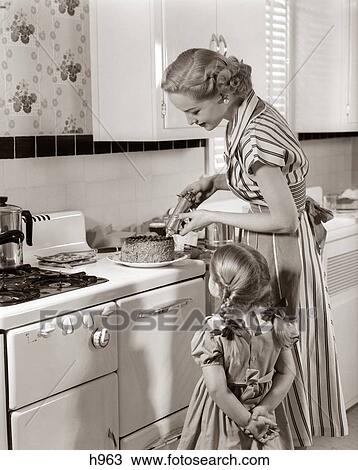 1950S Housewife In Kitchen Decorating Cake On Stove With Pastry Gun While Little Daughter Watches View Large Photo Image Stock Image - 1950S Housewife In Kitchen Decorating Cake On Stove With Pastry Gun While Little Daughter Watches. Fotosearch