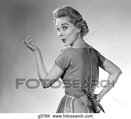 1950S Housewife Woman Wearing Apron Whistling In Surprise Pointing Hand Studio View Large Photo Image Picture - 1950S Housewife Woman Wearing Apron Whistling In Surprise Pointing Hand Studio. Fotosearch