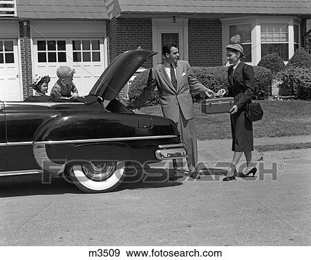 Stock Photo - 1950S Husband And Wife Packing Trunk Of Convertible With Luggage While Son & Daughter Watch From Back Seat. Fotosearch