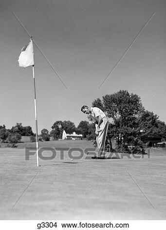 1950S Man Playing Golf Putting Golf Ball On Green To Flag And Cup Outdoor View Large Photo Image Picture - 1950S Man Playing Golf Putting Golf Ball On Green To Flag And Cup Outdoor. Fotosearch