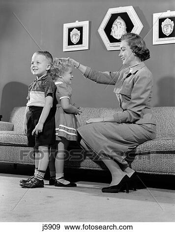 Stock Photo - 1950S Mother Measuring Difference In Height Between Son And Daughter Indoor. Fotosearch