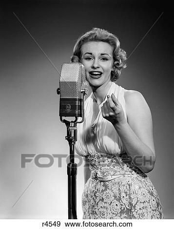 Stock Photo - 1950S Portrait Woman Entertainer Singing Into A Microphone Studio Looking At Camera. Fotosearch