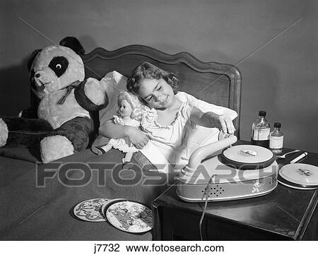 Stock Image - 1950S Sick Little Girl In Bed Playing With Record Player. Fotosearch