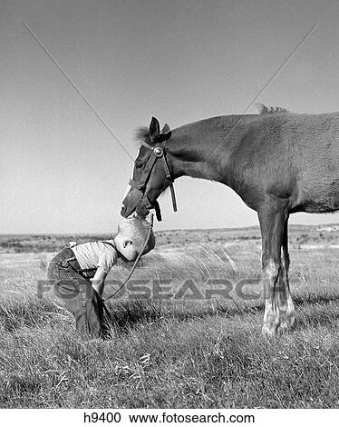 1950S Side View Of Little Blond Boy In Field Wearing Jeans & Suspenders Bending Down With Horse Licking Top Of Head View Large Photo Image Stock Image - 1950S Side View Of Little Blond Boy In Field Wearing Jeans & Suspenders Bending Down With Horse Licking Top Of Head. Fotosearch