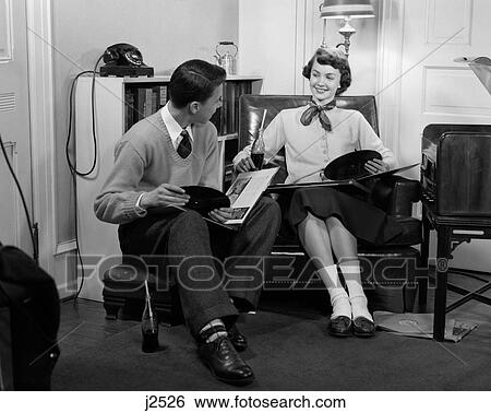 Stock Photograph - 1950S Teen Boy & Girl Sitting In Living Room Drinking Soda & Listening To Records. Fotosearch