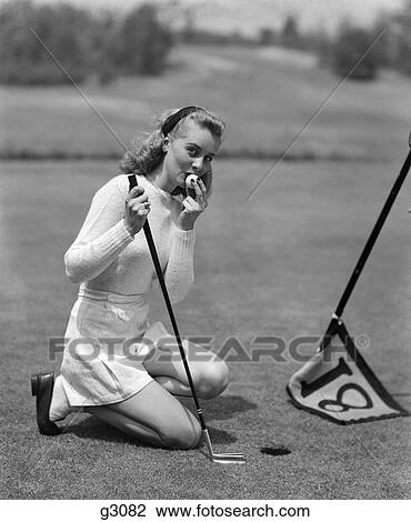 1950S Woman Golfer Kneeling By Cup In White Sports Sweater & Shorts Looking At Camera Kissing Golf Ball Making Putt On 18Th Hole View Large Photo Image Stock Image - 1950S Woman Golfer Kneeling By Cup In White Sports Sweater & Shorts Looking At Camera Kissing Golf Ball Making Putt On 18Th Hole. Fotosearch