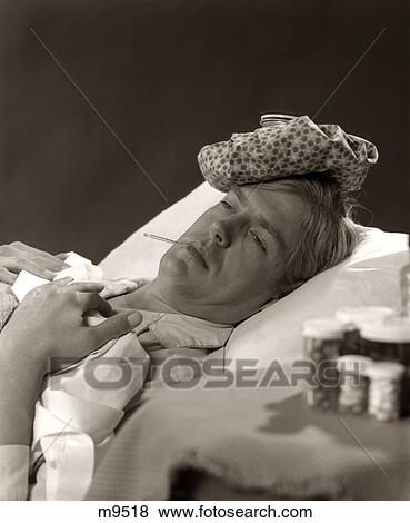 1960S 1970S Man In Sick In Bed With Thermometer In Mouth Ice Pack On Head Bottles Of Medicine Nearby View Large Photo Image Stock Photo - 1960S 1970S Man In Sick In Bed With Thermometer In Mouth Ice Pack On Head Bottles Of Medicine Nearby. Fotosearch