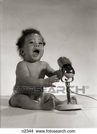1960S African-American Baby Seated In Front Of Old Fashioned Microphone With Mouth Open Broadcasting Radio View Large Photo Image Picture - 1960S African-American Baby Seated In Front Of Old Fashioned Microphone With Mouth Open Broadcasting Radio. Fotosearch