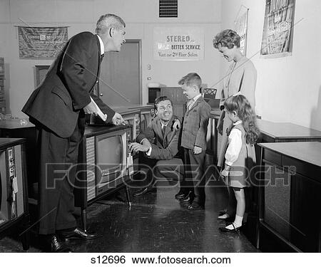 1960S Family In Tv Showroom Trying Set While Salesman Watches View Large Photo Image Stock Photograph - 1960S Family In Tv Showroom Trying Set While Salesman Watches. Fotosearch