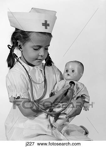 Stock Photo - 1960S Girl In Nurse Uniform Holding Stethoscope To Baby Doll Chest Indoor. Fotosearch