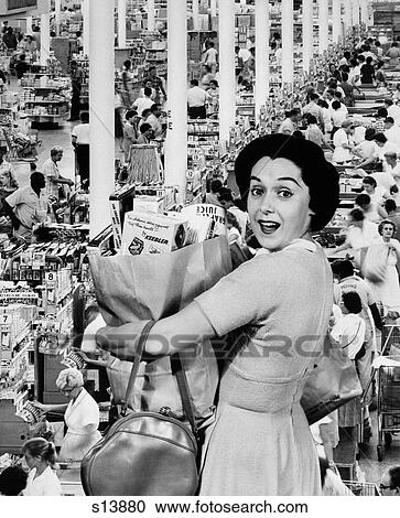 Stock Image - 1960S Housewife Looking At Camera Holding Grocery Bag Superimposed Over Grocery Store Check-Out Lines. Fotosearch