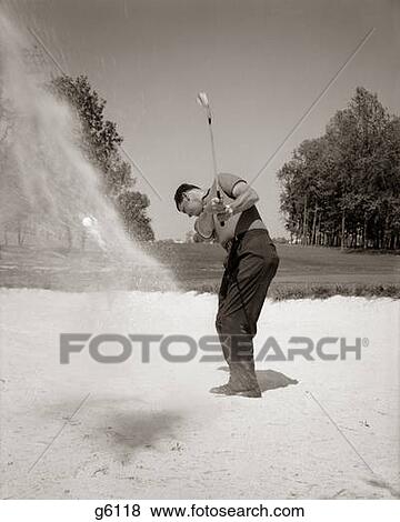 Stock Photo - 1960S Man Playing Golf Chipping Golf Ball Out Of A Sand Trap Outdoor. Fotosearch