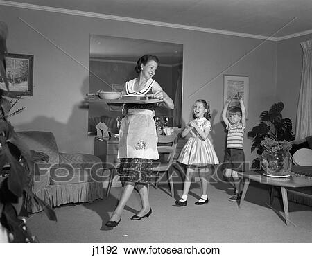 Stock Image - 1960S Mother Walking With Tray Of Snack Food Happy Son And Daughter Following Her Indoor. Fotosearch