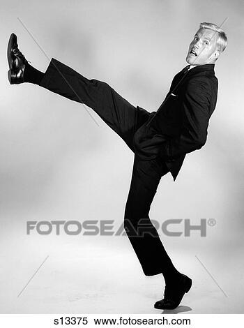 1960S Side View Of Man In Suit With Hands In Pockets Kicking A Foot And Leg Out High In The Air Looking At Camera View Large Photo Image Stock Photography - 1960S Side View Of Man In Suit With Hands In Pockets Kicking A Foot And Leg Out High In The Air Looking At Camera. Fotosearch