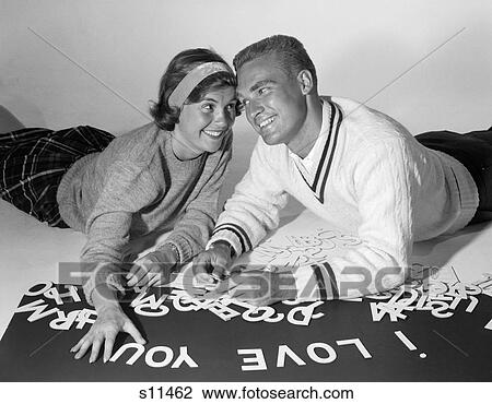 1960S Smiling Collegiate Couple Lying On Stomachs With Heads Pressed Together Spelling Out I Love You With Cut-Out Letters View Large Photo Image Stock Image - 1960S Smiling Collegiate Couple Lying On Stomachs With Heads Pressed Together Spelling Out I Love You With Cut-Out Letters. Fotosearch