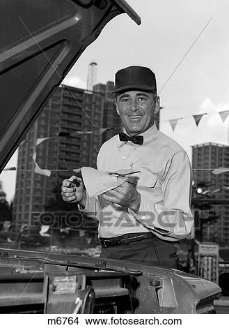 1960S Smiling Gas Station Attendant In Uniform Wiping Off Dipstick After Checking Oil View Large Photo Image Picture - 1960S Smiling Gas Station Attendant In Uniform Wiping Off Dipstick After Checking Oil. Fotosearch