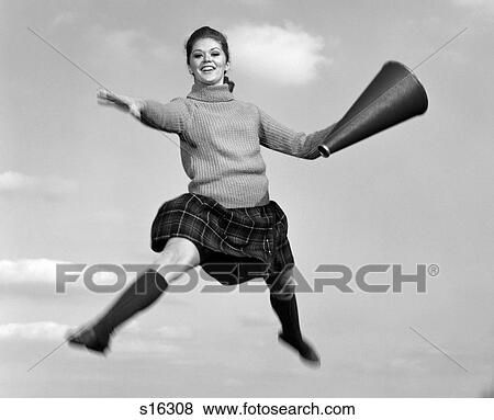 1960S Teen Girl Cheerleader Jumping Doing Split In Air With Megaphone Outdoor Looking At Camera View Large Photo Image Stock Photo - 1960S Teen Girl Cheerleader Jumping Doing Split In Air With Megaphone Outdoor Looking At Camera. Fotosearch