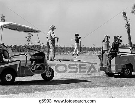 1960S Three Men Playing Golf Teeing Off From Tee With Driver Near Golf Carts Outdoor View Large Photo Image Stock Image - 1960S Three Men Playing Golf Teeing Off From Tee With Driver Near Golf Carts Outdoor . Fotosearch