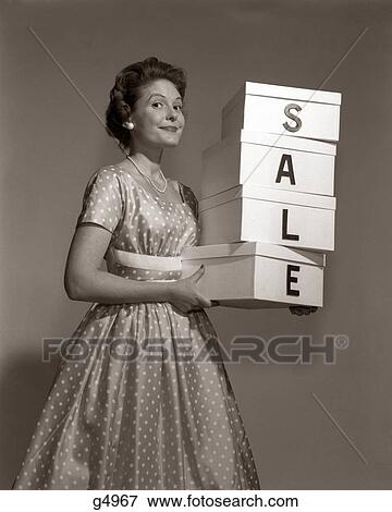1960S Woman In Polka-Dot Dress Looking At Camera Holding A Stack Of 4 Boxes With One Character Centered On Each Spelling Sale View Large Photo Image Stock Photo - 1960S Woman In Polka-Dot Dress Looking At Camera Holding A Stack Of 4 Boxes With One Character Centered On Each Spelling Sale. Fotosearch
