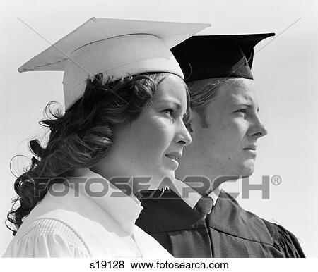 1970S Close-Up Of Two Graduates In Cap & Gown Male In Black & Female In White Looking Off Into Distance View Large Photo Image Stock Photo - 1970S Close-Up Of Two Graduates In Cap & Gown Male In Black & Female In White Looking Off Into Distance. Fotosearch