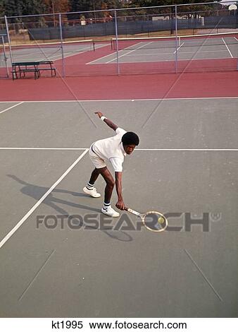 1970S Man African-American Playing Tennis Leaning Over About To Hit Ball Low Backhand View Large Photo Image Stock Photography - 1970S Man African-American Playing Tennis Leaning Over About To Hit Ball Low Backhand . Fotosearch