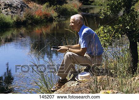 1980S Older Man Sitting By The Stream Holding Bibles View Large Photo Image Stock Photo - 1980S Older Man Sitting By The Stream Holding Bibles . Fotosearch