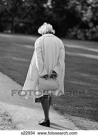 1980S Rear View Of Elderly Woman Walking Down Sidewalk Holding Purse Behind Back Head Down View Large Photo Image Picture - 1980S Rear View Of Elderly Woman Walking Down Sidewalk Holding Purse Behind Back Head Down. Fotosearch
