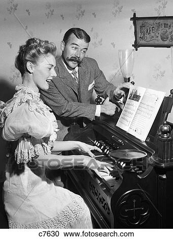 1900S Couple In Turn Of The Century Dress Woman Playing Parlor Organ Man With Handlebar Mustache Turns Pages Of Sheet Music View Large Photo Image Stock Image - 1900S Couple In Turn Of The Century Dress Woman Playing Parlor Organ Man With Handlebar Mustache Turns Pages Of Sheet Music. Fotosearch
