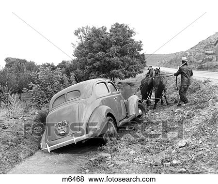 1930S 1937 Ford V-8 Being Pulled Out Of Rural Road Ditch By Man With Team Of Two Horses View Large Photo Image Stock Photo - 1930S 1937 Ford V-8 Being Pulled Out Of Rural Road Ditch By Man With Team Of Two Horses . Fotosearch