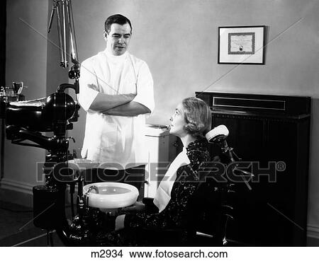 1930S 1940S Man Dentist Arms Crossed Talking To Woman Patient Sitting In Dental Chair View Large Photo Image Picture - 1930S 1940S Man Dentist Arms Crossed Talking To Woman Patient Sitting In Dental Chair. Fotosearch