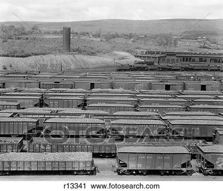 Stock Image - 1930S 1940S Railroad Yard With Engine Roundhouse And Many Boxcars And Hopper Cars Full Of Coal. Fotosearch