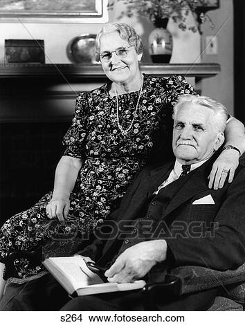 1940S Portrait Smiling Senior Couple Man Woman Sitting In Easy Chair Looking At Camera View Large Photo Image Picture - 1940S Portrait Smiling Senior Couple Man Woman Sitting In Easy Chair Looking At Camera. Fotosearch
