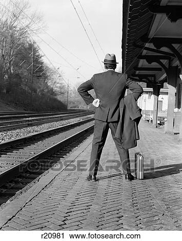 1950S 1960S Man Commuter Back View Standing Hands On Hips Briefcase Waiting For Train Or Missed A Train View Large Photo Image Stock Image - 1950S 1960S Man Commuter Back View Standing Hands On Hips Briefcase Waiting For Train Or Missed A Train . Fotosearch