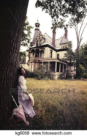1960S 1970S Woman Standing Beside Tree Front Of Abandoned Haunted Victorian House View Large Photo Image Stock Photo - 1960S 1970S Woman Standing Beside Tree Front Of Abandoned Haunted Victorian House. Fotosearch