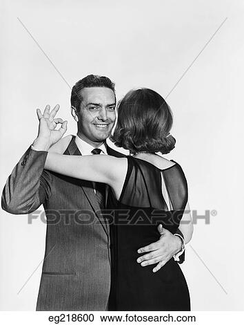 1960S Couple Dancing Man Looking At Camera Making Okay Gesture Behind Woman'S Back View Large Photo Image Stock Image - 1960S Couple Dancing Man Looking At Camera Making Okay Gesture Behind Woman'S Back. Fotosearch